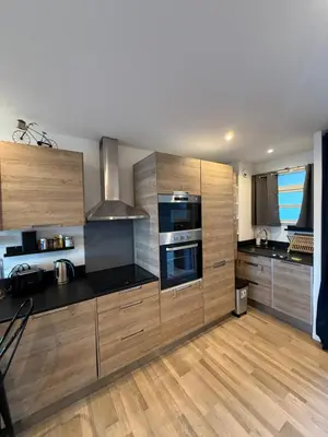a kitchen with wooden cabinets and stainless steel appliances at Air-conditioned studio comfort & cozy in Saint-Laurent-du-Var