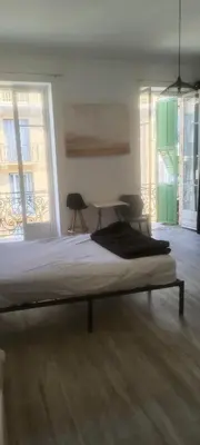 a bed in a room with a table and windows at très grande chambre climatisée plein centre Nice avec balcon in Nice