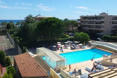 a large swimming pool with people sitting around it at Nice Seaside Appartement with Pool and Tennis in Saint-Laurent-du-Var