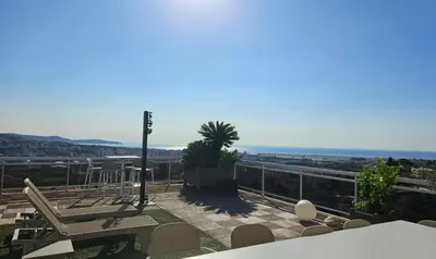 a patio with chairs and a view of the ocean at Penthouse - Vue mer panoramique - SPA privé - Piscine commune in Saint-Laurent-du-Var