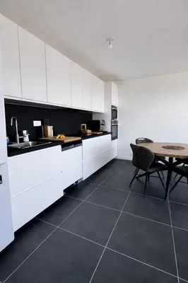 a kitchen with white cabinets and a table in it at Luxury apartment with balcony & rooftop in Nice