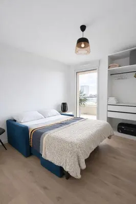 a white bedroom with a blue bed and a window at Luxury apartment with balcony & rooftop in Nice