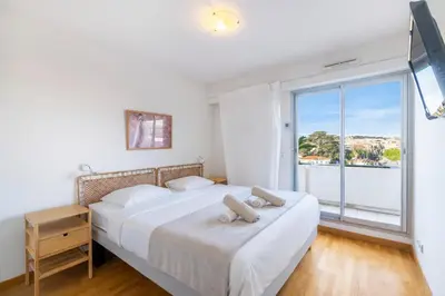 a bedroom with a bed and a large window at 2BR Sea View Apartment with Pool & AC in Cagnes-sur-Mer