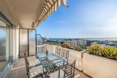 a balcony with a glass table and chairs at 2BR Sea View Apartment with Pool & AC in Cagnes-sur-Mer