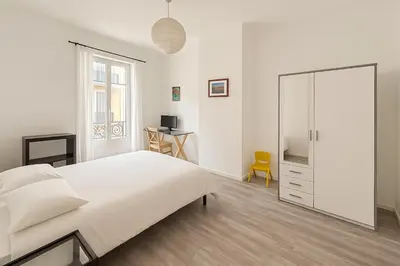 a white bedroom with a bed and a mirror at Large 1 bedroom apartment, balcony, very central Nice in Nice