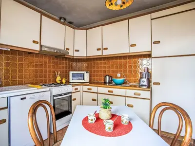 a kitchen with white cabinets and a table with chairs at Holiday Home Maison Valensole by Interhome in Cagnes-sur-Mer