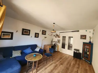 a living room with a blue couch and a wooden table at Charmant 2 pièces in Nice