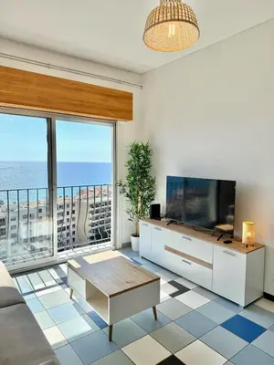 a living room with a tv and a large window at Vue mer panoramique, plage et Promenade à pied in Nice