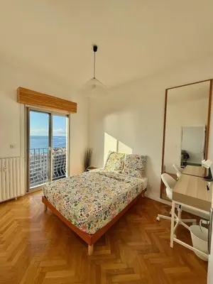 a bedroom with a bed and a desk and a window at Vue mer panoramique, plage et Promenade à pied in Nice