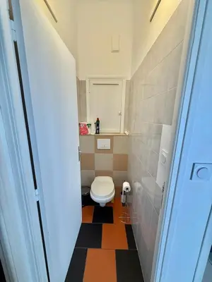 a small bathroom with a toilet and a tiled floor at Vue mer panoramique, plage et Promenade à pied in Nice