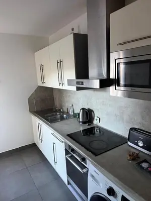 a kitchen with white cabinets and a stove top oven at Appartement 3 chambres avec piscine et parking privé in Nice