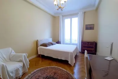 a bedroom with a bed and a chair and a window at Large bright apartment in the heart of Nice in Nice