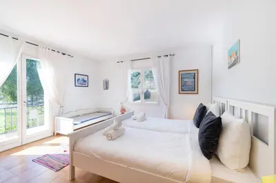 a white bedroom with two beds and windows at Villa in Cagnes-sur-Mer in Cagnes-sur-Mer