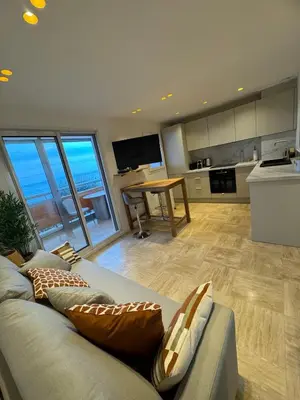 a living room with a couch and a kitchen at Le California front de mer in Cagnes-sur-Mer