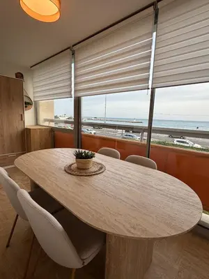 a dining room table with chairs and a large window at Le California front de mer in Cagnes-sur-Mer