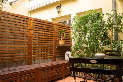 a wooden privacy fence with a bench and a table at Duplex carré d'or au calme sur cour 100m de la plage in Nice