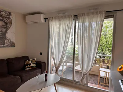 a living room with a couch and a large window at Charmant Studio Proche Plage et Transport in Saint-Laurent-du-Var