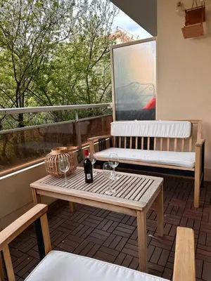 a wooden table and bench on a balcony with a window at Charmant Studio Proche Plage et Transport in Saint-Laurent-du-Var