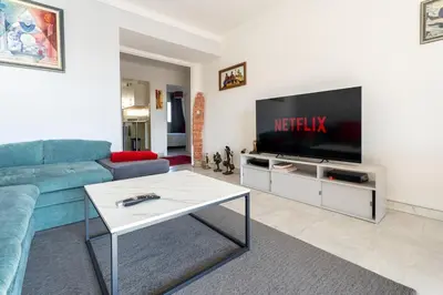 a living room with a blue couch and a tv at Le Concorde in Saint-Laurent-du-Var