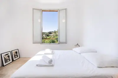 a white bedroom with a large bed with a window at House on the Hill in Nice