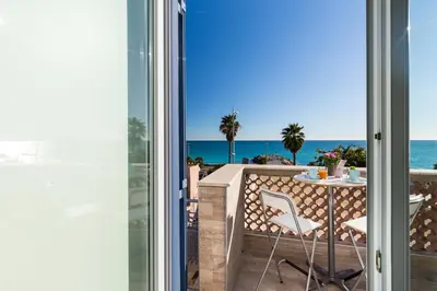 a room with a view of the ocean from a balcony at La Maison Du Pêcheur in Cagnes-sur-Mer