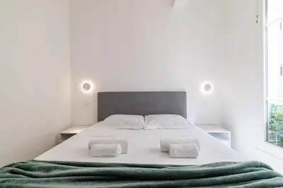 a white bedroom with a large bed with two pillows at B G Cocon Meyerbeer 2 - Grimaldi Promenade des Ang in Nice