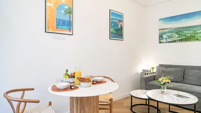 a living room with a table and a couch at B G Cocon Meyerbeer 2 - Grimaldi Promenade des Ang in Nice