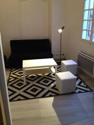 a living room with a black couch and two stools at Place Rossetti - Charming Apartment in Nice