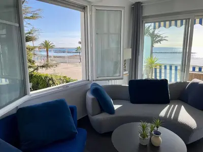 a living room with a couch and a view of the beach at Appartement Pieds dans l'eau in Saint-Laurent-du-Var
