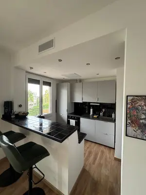a kitchen with white cabinets and a black counter top at 2 pièces rénové avec magnifique vue mer et parking in Nice