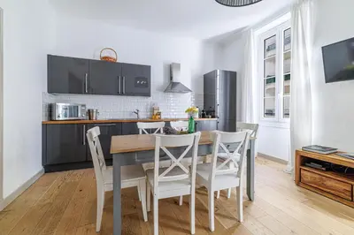 a kitchen with a wooden table and white chairs at Wide & Central 3 Bdr - AC & Balcony in Nice