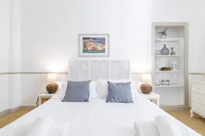 a white bedroom with a white bed with blue pillows at Wide & Central 3 Bdr - AC & Balcony in Nice