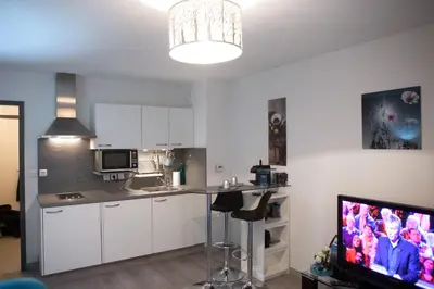 a kitchen with white cabinets and a flat screen tv at Villa Lympia in Nice