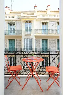 a red table and chairs on a balcony with a building at La Romantica Dante Five stars Holiday House in Nice