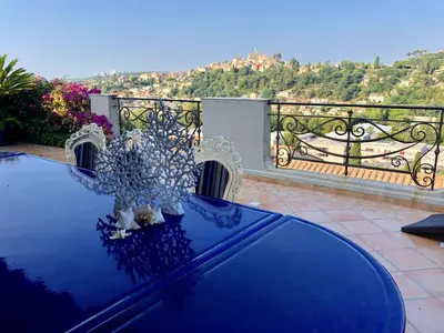 a blue table with flowers on top of a balcony at Les Grimaldines - Maison d'Hôtes in Cagnes-sur-Mer