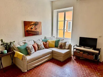 a living room with a couch and a television at Résidence Place Poullan in Villefranche-sur-Mer