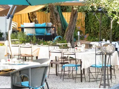 a group of tables and chairs under an umbrella at Hotel mon Soleil in La Gaude