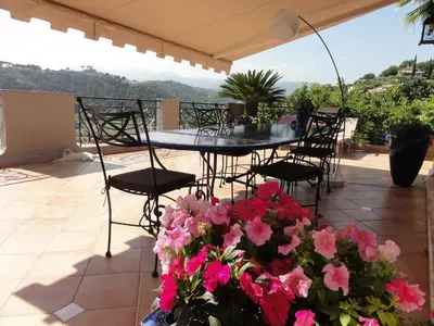 a table and chairs on a patio with pink flowers at Villa les grimaldines côte d Azur in Cagnes-sur-Mer