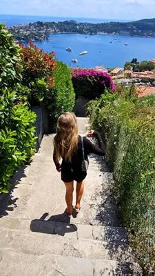 a young girl walking down a path near a body of water at Hôtel La Fiancée du Pirate in Villefranche-sur-Mer