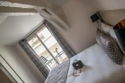 a camera on a bed in a room with a window at Hotel Saint Gothard in Nice