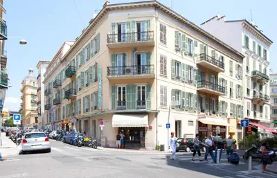 a building on a city street with people walking on the sidewalk at Hotel Saint Gothard in Nice