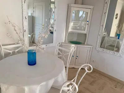 a white table and chairs in a room with mirrors at Appartement sur la Plage, Le Royal Beach in Saint-Laurent-du-Var