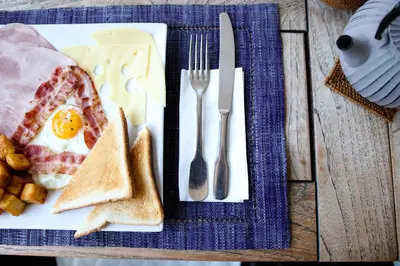 a plate of food with an egg and bread and utensils at Le Panoramic Boutique Hôtel in Nice