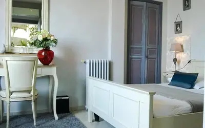 a bedroom with a bed and a desk and a vase with flowers at Le Panoramic Boutique Hôtel in Nice