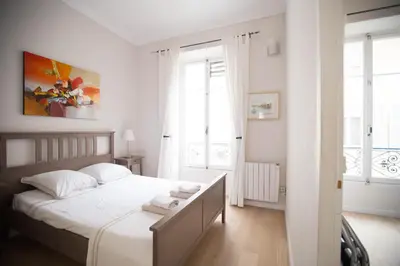 a white bedroom with a bed with towels on it at Le Coin Du Marché in Nice