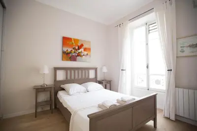 a bedroom with a bed with white sheets and a window at Le Coin Du Marché in Nice
