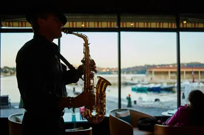 a man playing a saxophone in front of a window at Welcome Hotel in Villefranche-sur-Mer