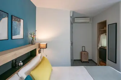 a bedroom with a white bed and a blue wall at Bristol Nice in Nice