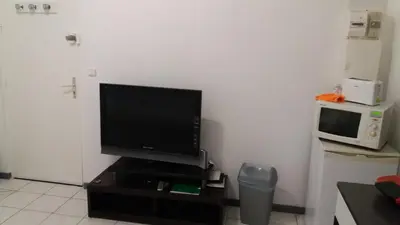 a living room with a television and a microwave at Studio dans la Villa 
