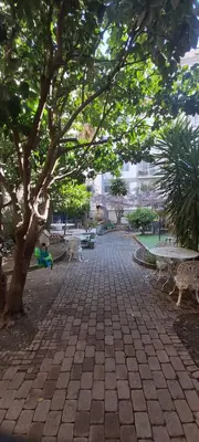 a brick walkway with benches and trees in a park at Studio dans la Villa 